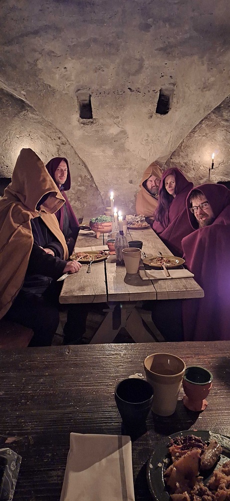 Members of Avalon Larp Studio, the Transformative Play Initiative, and Chaos League in cloaks at a medieval restaurant